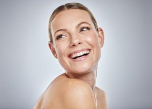 Mujer recibiendo tratamiento facial iluminador profesional en clínica estética preparándose para eventos navideños con piel radiante luminosa