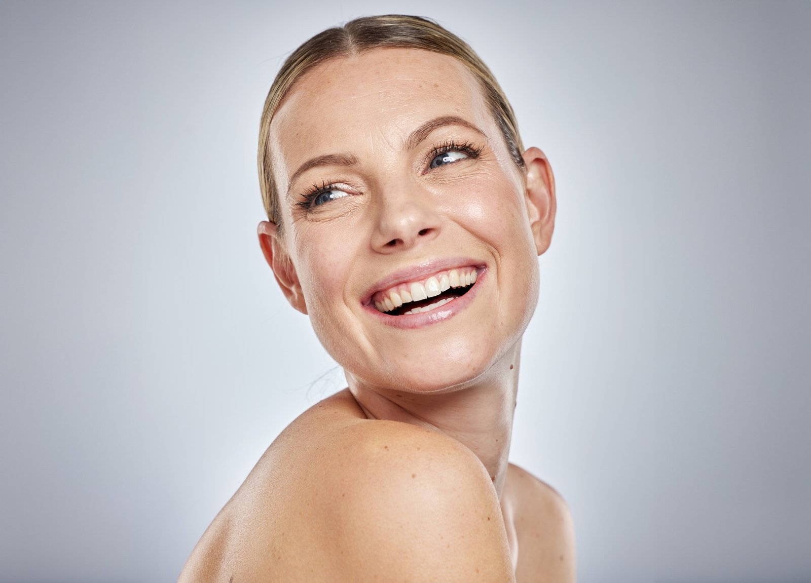 Mujer recibiendo tratamiento facial iluminador profesional en clínica estética preparándose para eventos navideños con piel radiante luminosa