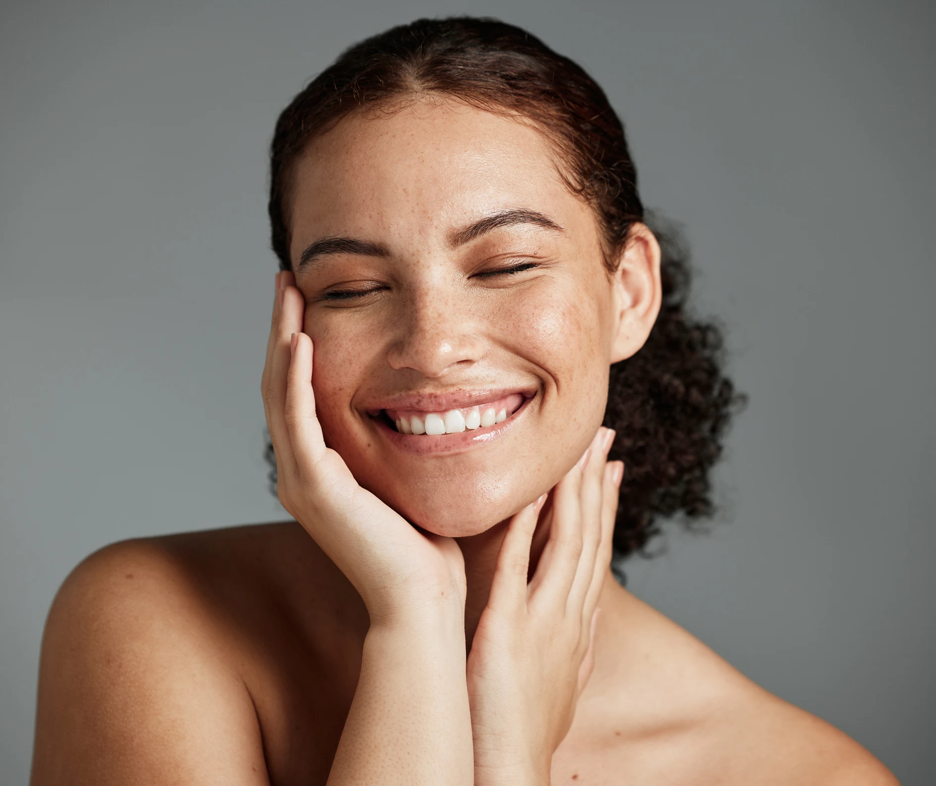 Mujer feliz mirándose al espejo después tratamiento facial año nuevo mostrando piel radiante transformada en clínica estética BCNClinic Barcelona